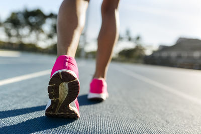 Legs of female athlete running on racetrack