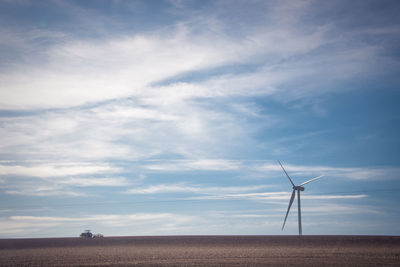 Wind turbines on field against sky