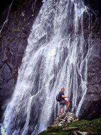 Full length of man standing against waterfall