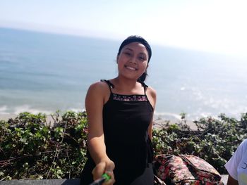 Portrait of young woman standing against sea
