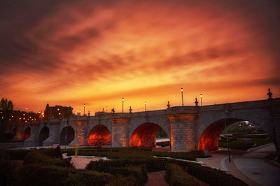 Arch bridge over river against sky during sunset