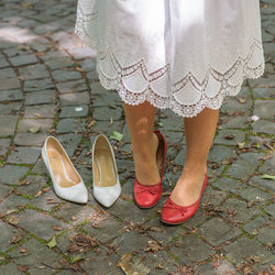 A detail of a bride changing shoes in the wedding dress outdoors in a park.