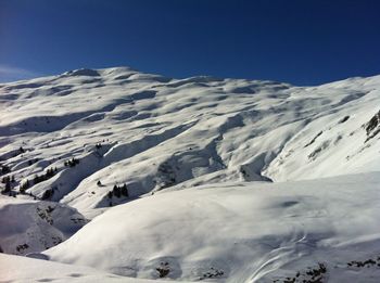 Scenic view of snowcapped mountains against clear blue sky
