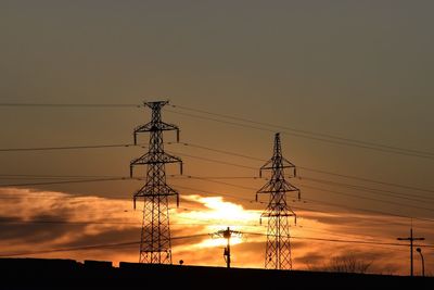 Low angle view of silhouette electricity pylon against romantic sky