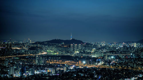 High angle shot of illuminated cityscape against blue sky