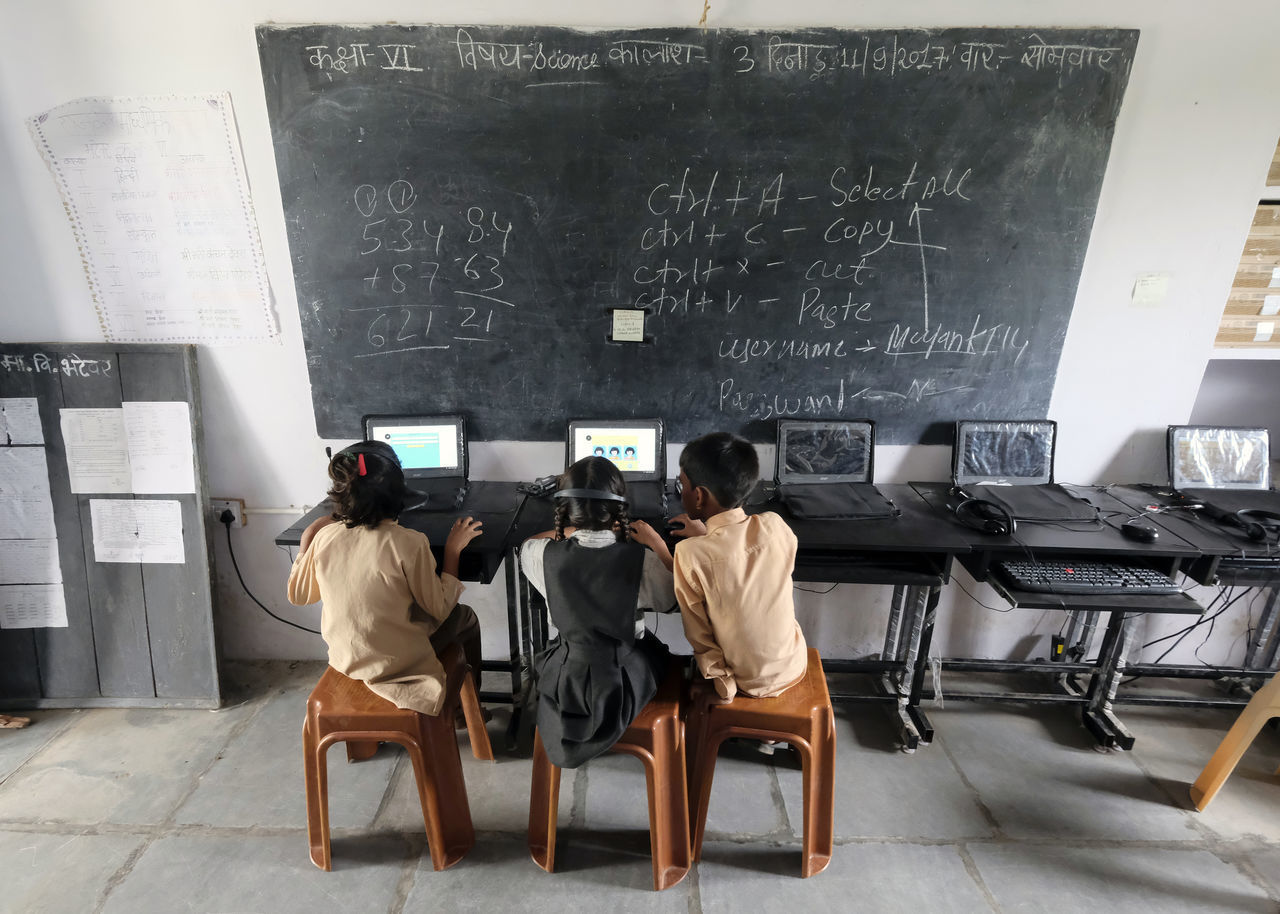 REAR VIEW OF PEOPLE SITTING ON CHAIR AT TABLE