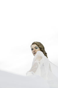 Low angle view of woman with shiny make-up against white background