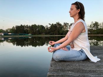 Side view of woman doing yoga on pier over lake