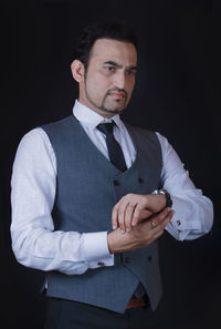 Young man standing against black background