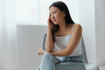 Young woman sitting on sofa at home