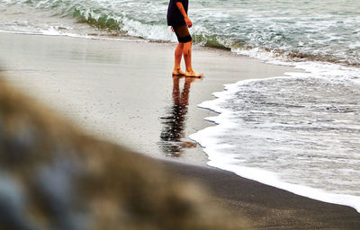 Low section of woman standing on beach