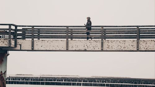 Low angle view of man standing on bridge against sky