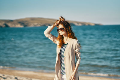 Woman with umbrella standing on beach