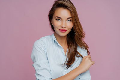 Portrait of young woman standing against wall