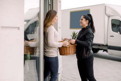 Delivery woman delivering fruits to mature female customer