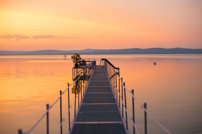 Pier over sea against sky during sunset