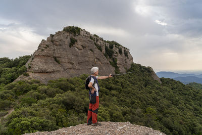 Hiker showing with hiking pole, standing on viewpoint