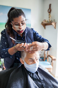 Beautician treating hair of customer at home