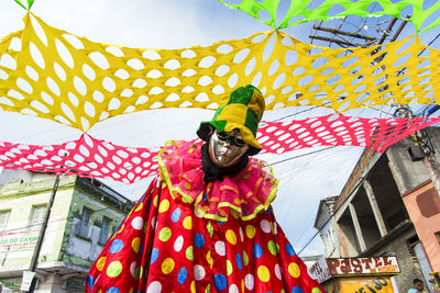 Person seated wearing carnival mask