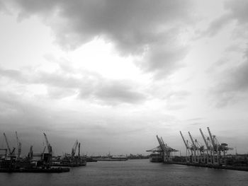 Boats moored at harbor against cloudy sky