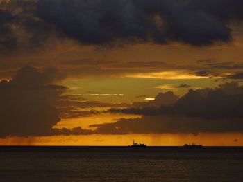 Scenic view of sea against dramatic sky during sunset