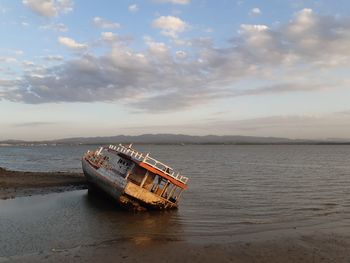 Abandoned boat in sea against sky