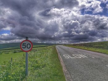 Road sign against cloudy sky