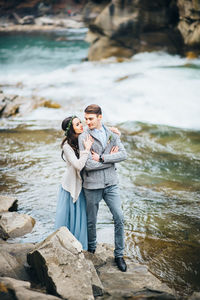 Couple standing on rock by sea