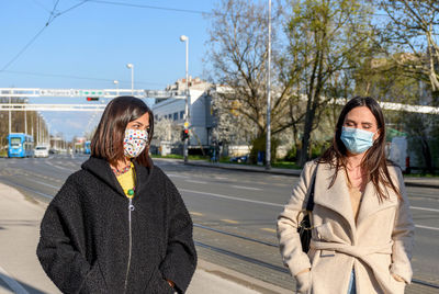 Two friends walking in city, wearing protective masks during corona virus epidemic, female, women.