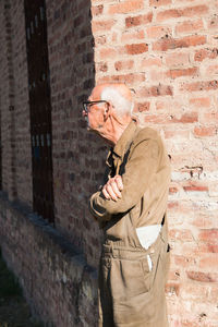 Senior man standing against bricked wall