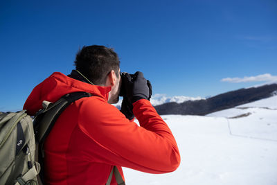 Rear view of man taking image on snow