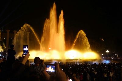 People at fountain against sky at night