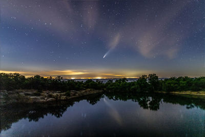 Comet neowise above the ocean horizon reflecting in the water below.