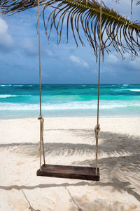 Empty wooden swing at sandy beach