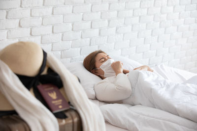 Woman wearing mask while lying on bed at home