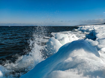 Scenic view of sea waves splashing against blue sky