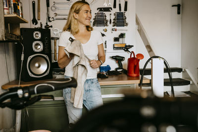 Smiling confident female owner standing in bicycle shop