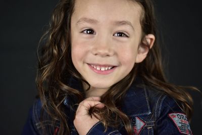 Portrait of smiling girl against black background