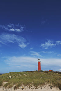 Lighthouse on street amidst buildings against sky