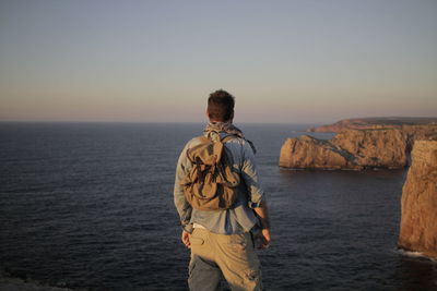 Rear view of man standing in sea against clear sky