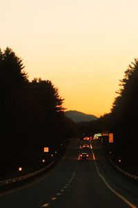 Cars on road against sky at sunset