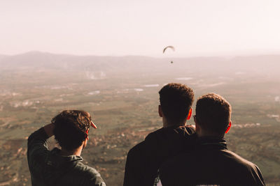 Rear view of men on landscape against sky