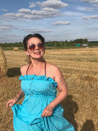 Portrait of smiling woman wearing sunglasses standing in farm