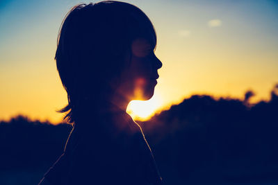 Close-up portrait of silhouette child against sky during sunset