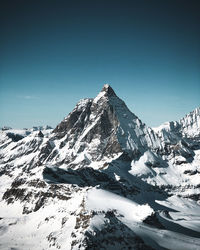 Scenic view of snowcapped mountains against clear blue sky