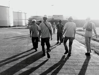 Rear view of workers walking towards factory