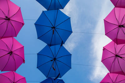 Low angle view of pink and vlue umbrella against blue sky