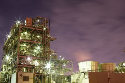 Low angle view of illuminated industrial area against sky