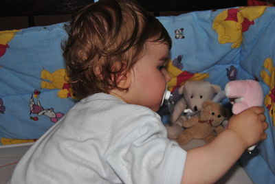 Cute baby boy sucking pacifier while playing with toys at home