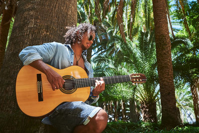 Man playing guitar against trees